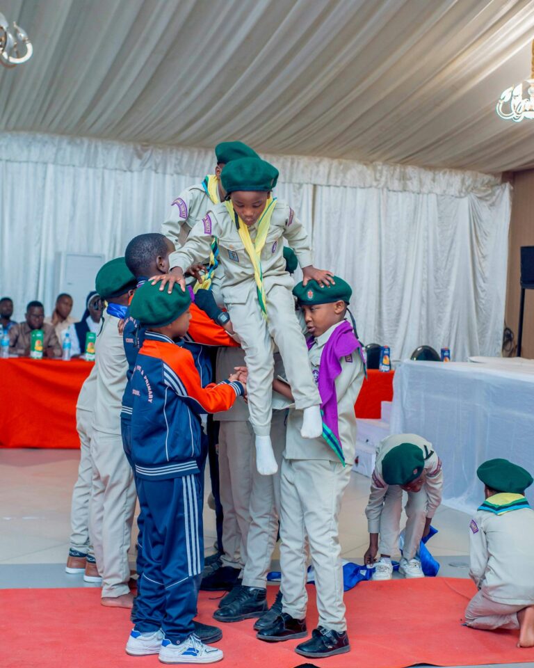Group of youth scouts participating in a team-building exercise indoors.